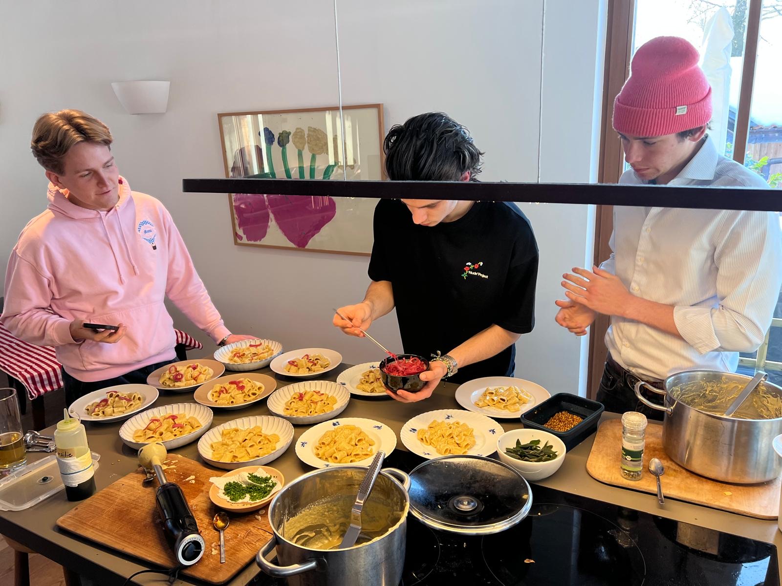 Leo plating a private dinner — guests gathered around the kitchen counter